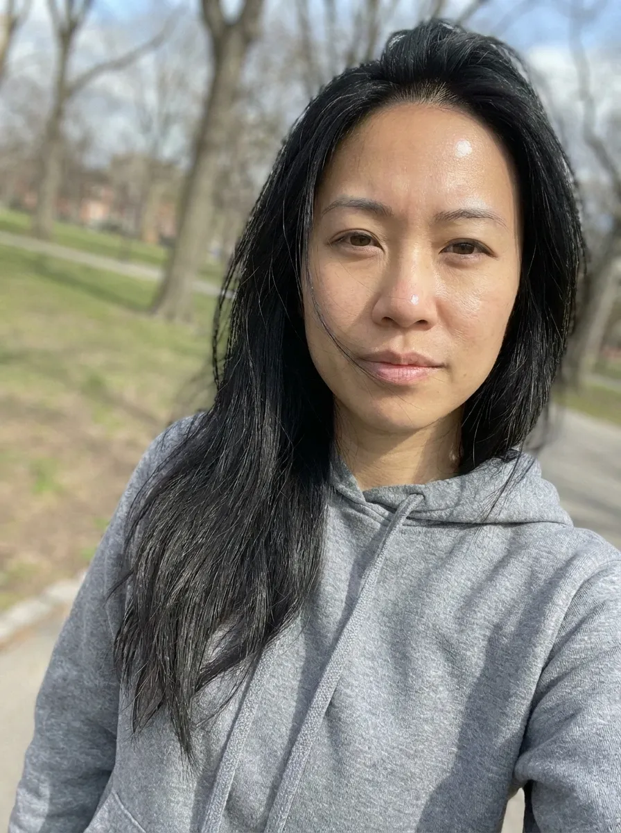 Original selfie input — woman in a gray hoodie outdoors